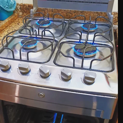 Fogão inox de 4 bocas com grelhas e chamas azuis após revisão completa